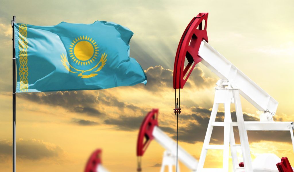 Oil rigs against the backdrop of the colorful sky and a flagpole with the flag of Kazakhstan. The concept of oil production, minerals, development of
