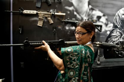 An Indian woman tries out an assault wea