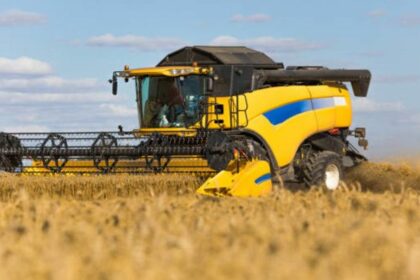 Yellow combine harvester on a wheat field with blue sky.