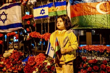 An Azerbaijani child outside the Israeli embassy in Baku which is adorned with flowers and candles October 9 2023. 1200x675