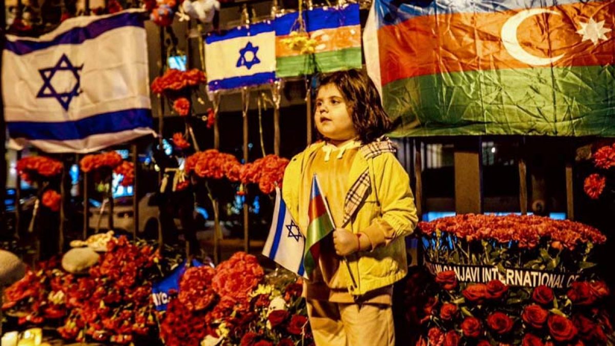 An Azerbaijani child outside the Israeli embassy in Baku which is adorned with flowers and candles October 9 2023. 1200x675